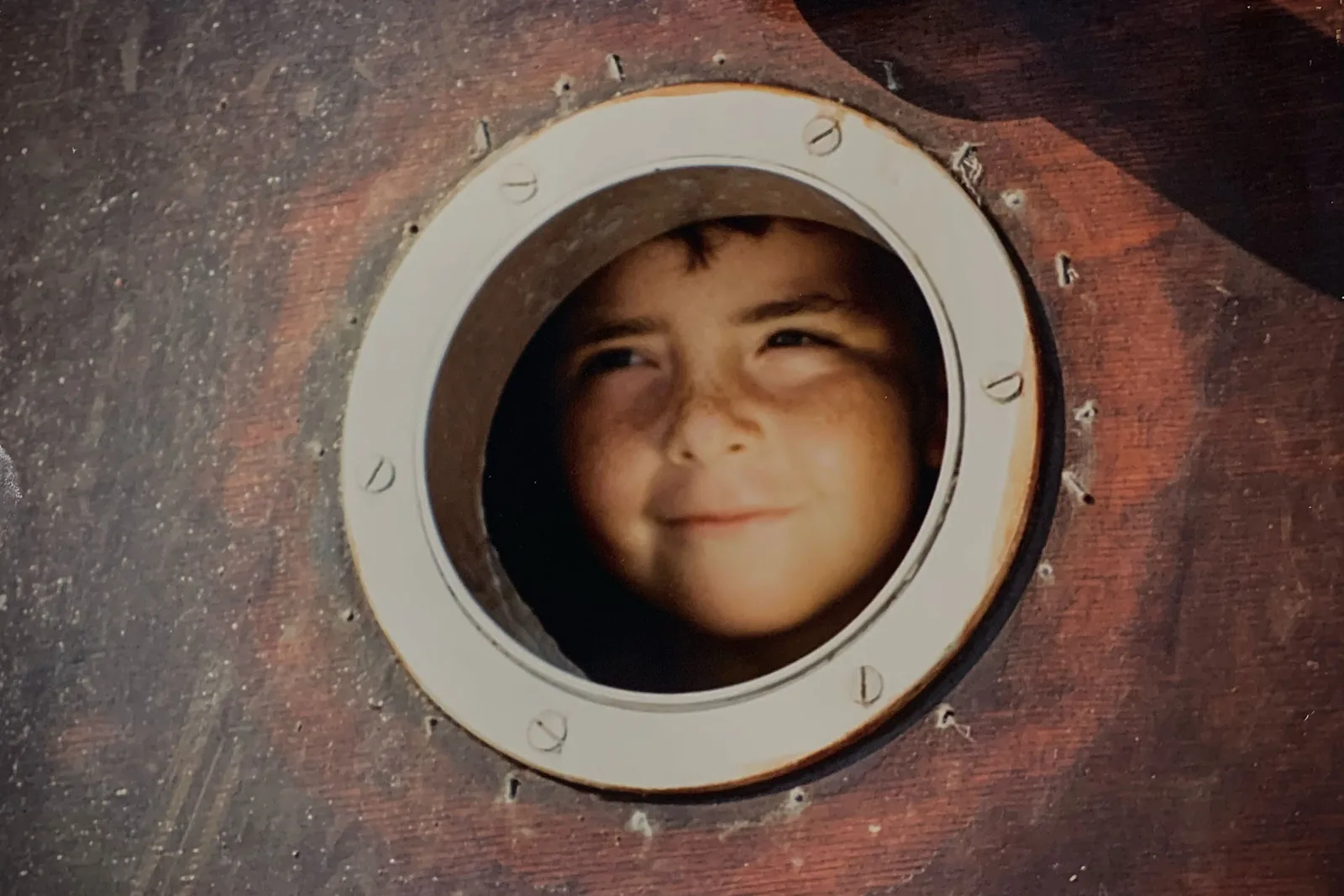 Salvatore Frisina as a child looking through a ship porthole